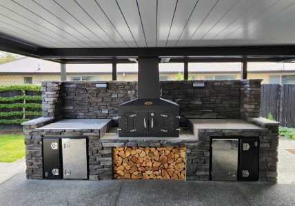 Engel Fire outdoor kitchen with built-in stone surround and ceiling vent for smoke control.